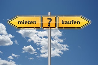 Gelbes Straßenschild mit den Optionen ‚mieten‘ und ‚kaufen‘ vor blauem Himmel
