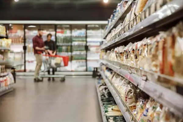 Person steht vor Regal mit Waren im Supermarkt