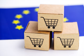 Drei kleine Versandkartons vor EU-Flagge