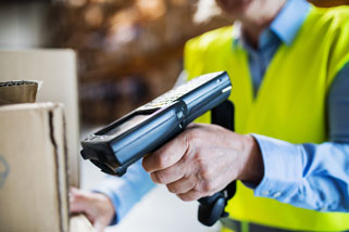 Person scannt Paket mit Handscanner im Lager