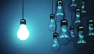 Mehrere Glühbirnen vor blauem Hintergrund, eine leuchtet